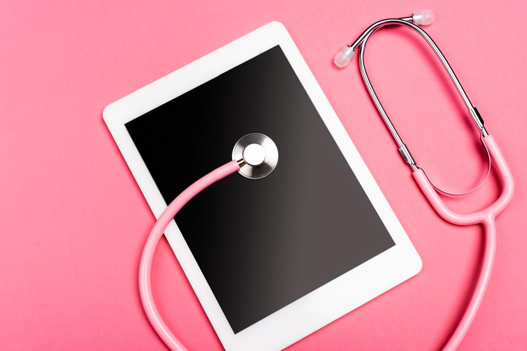 Draufsicht auf Stethoskop auf digitalem Tablet mit leerem Bildschirm auf rosa Hintergrund - Foto, Bild