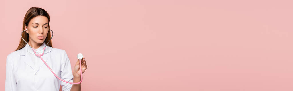 Orvos fehér köpenyben tartja sztetoszkóp izolált rózsaszín, banner  - Fotó, kép
