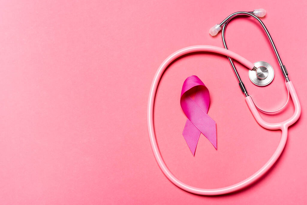 Horní pohled na stetoskop a symbol povědomí o rakovině prsu na růžovém povrchu  - Fotografie, Obrázek