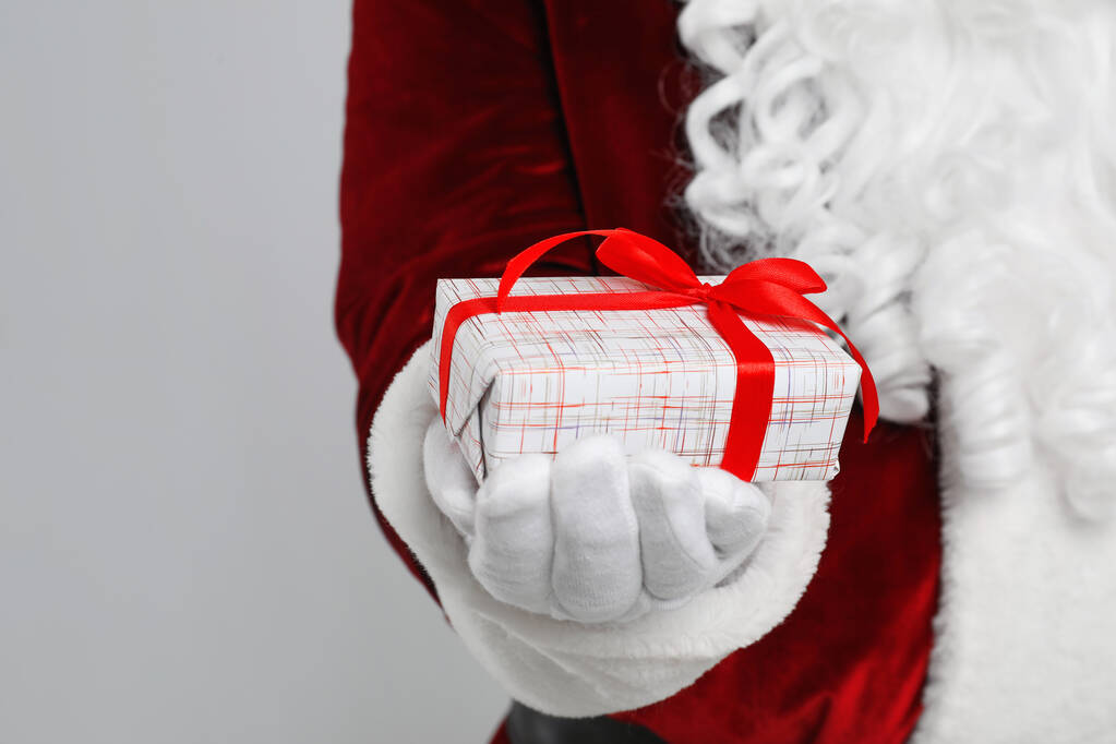 Weihnachtsmann mit Weihnachtsgeschenk auf hellgrauem Hintergrund, Nahaufnahme - Foto, Bild