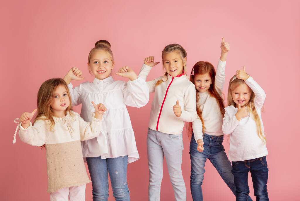 Портрет маленьких кавказских детей с яркими эмоциями на фоне розовой студии - Фото, изображение