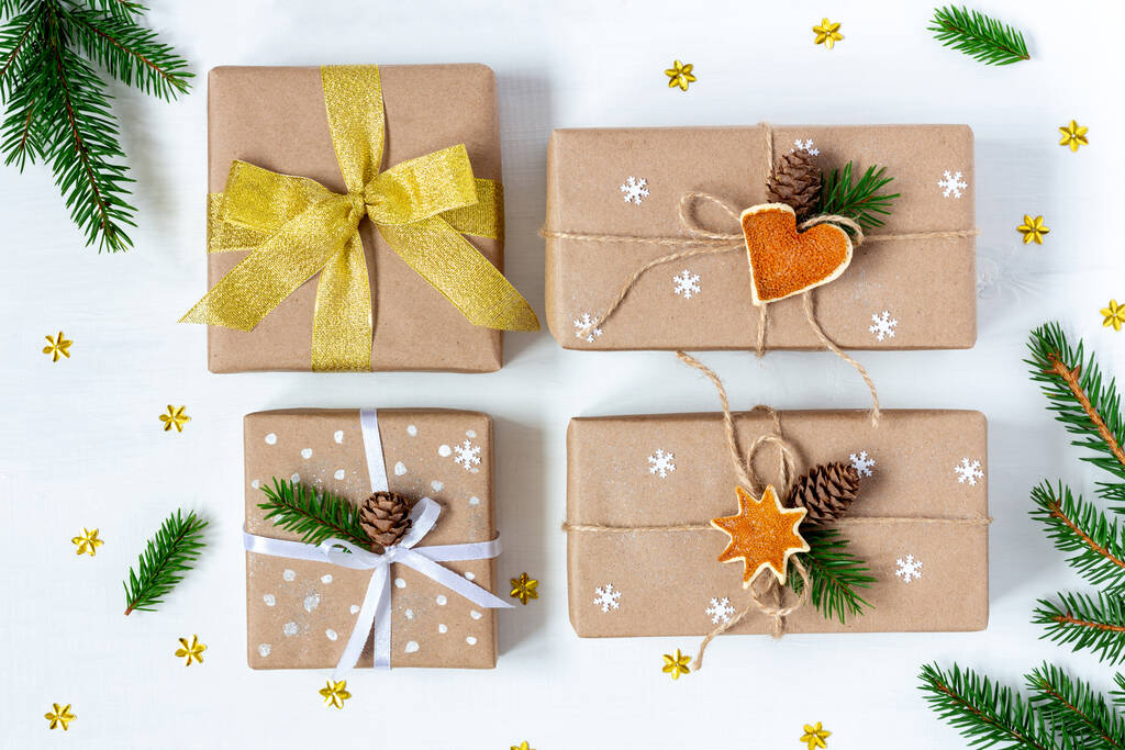 Vier kerst- en nieuwjaarscadeaus verpakt in eco-papier op witte houten achtergrond - Foto, afbeelding