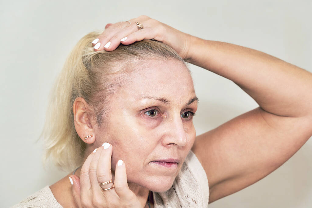 Blondýnka drží své vlasy a aplikuje základ na její tvář - Fotografie, Obrázek