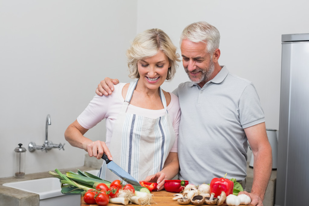 Happy mature couple preparing food together in kitchen - Photo, Image