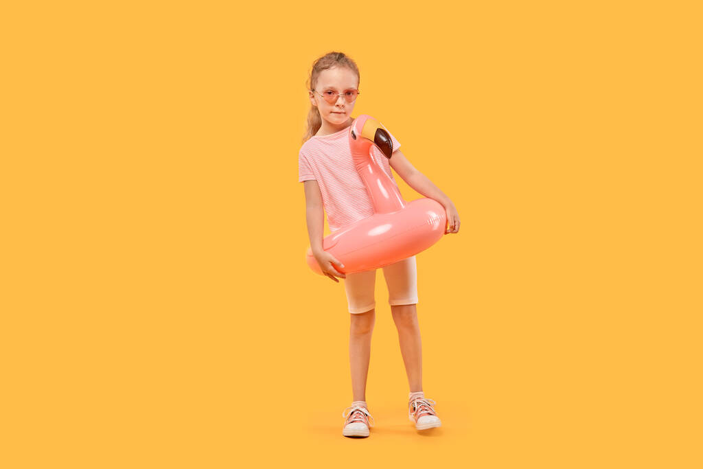 Menina bonito em óculos de sol com um círculo inflável na forma de um Flamingo. - Foto, Imagem