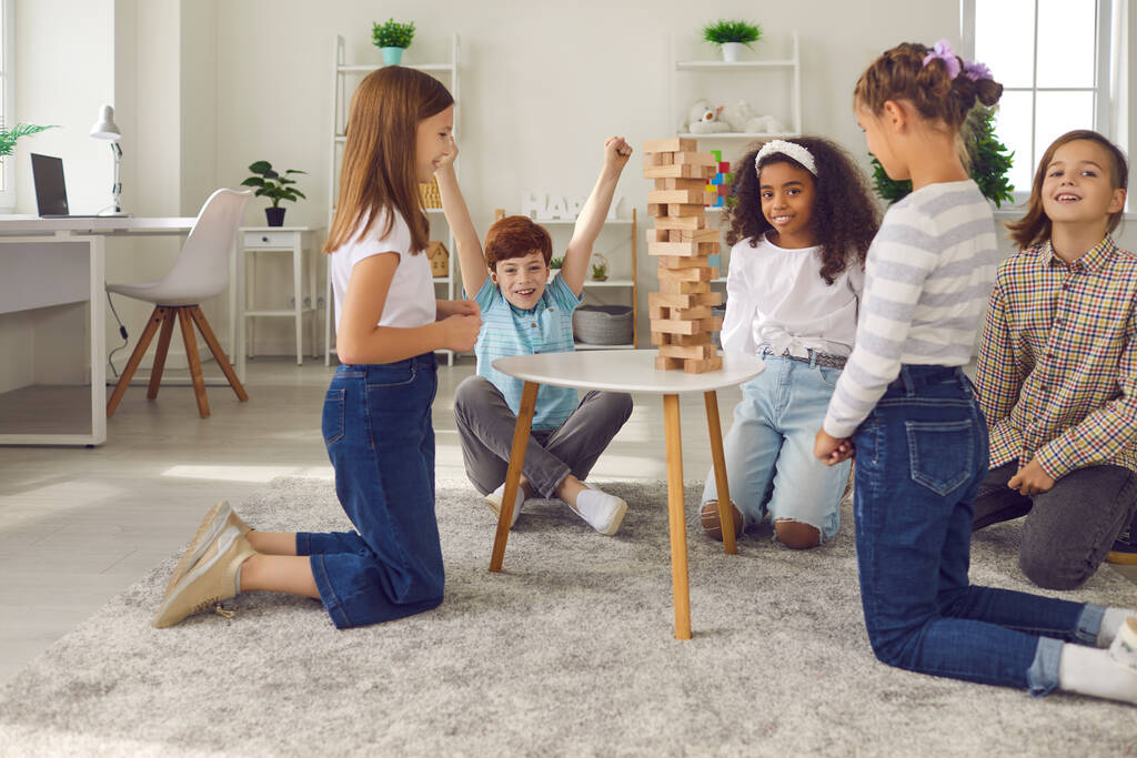 Gruppo di bambini felici che giocano a torretta di legno impilando il gioco a casa o nel club del tempo libero dopo la scuola - Foto, immagini