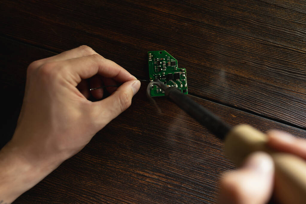 Un hombre repara una placa eléctrica con un soldador - Foto, imagen