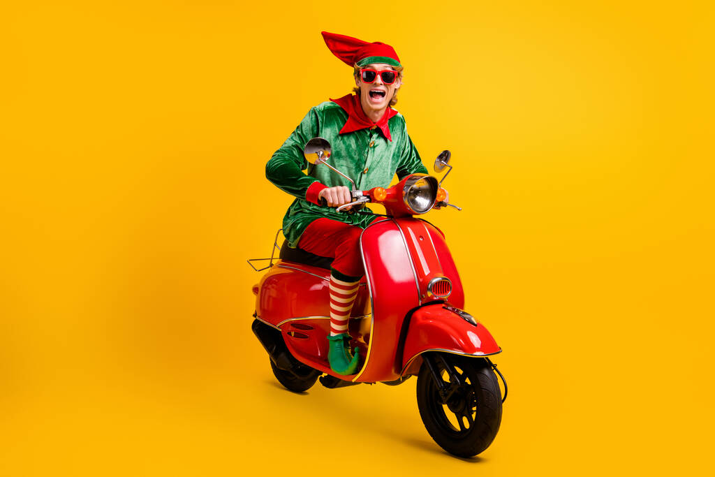 Portret jego miły atrakcyjny wesoły wesoły wesoły zadowolony ekstatyczny zabawny facet elf jazda czerwony motorower mając zabawy festal wygląd sprzedaży zniżki izolowane nad jasny żywy połysk żywy żółty kolor tło - Zdjęcie, obraz