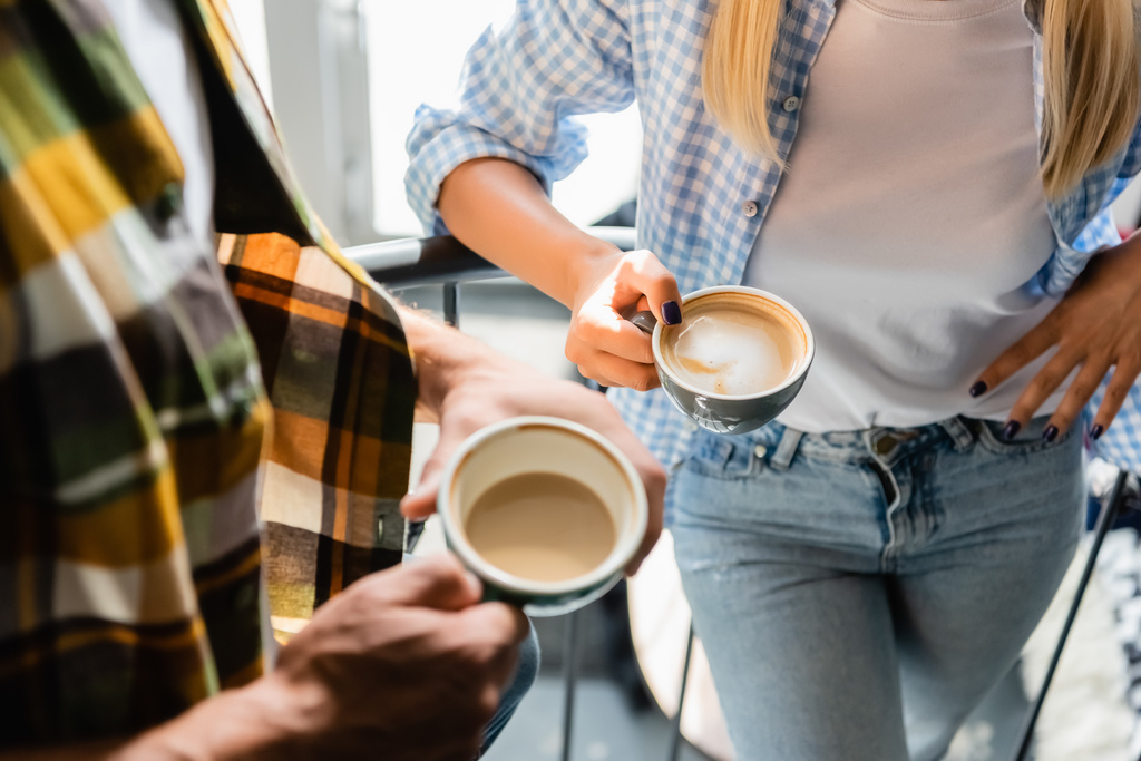 vista ritagliata di uomo e donna in possesso di tazze con cappuccino in caffè - Foto, immagini