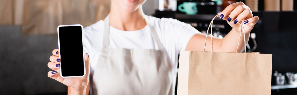 przycięty widok kelnera trzymającego papierową torbę i smartfona z pustym ekranem, baner - Zdjęcie, obraz