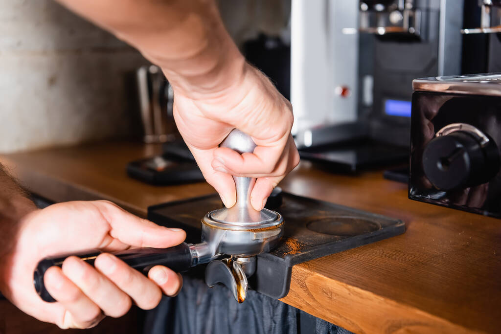 vista recortada de barista presionando café molido en portafilter - Foto, imagen