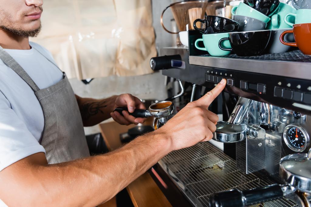 Kahve makinesindeki kahve makinesine basan baristanın portafilter tutarken kırpılmış görüntüsü - Fotoğraf, Görsel