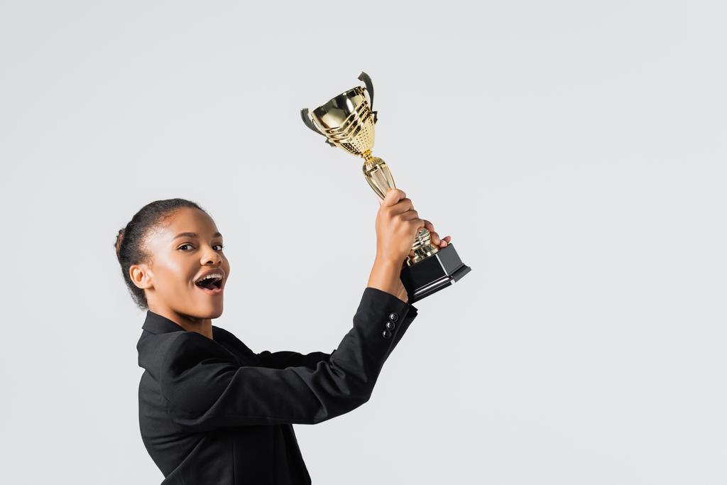 happy african american businesswoman with golden cup isolated on grey - Photo, Image