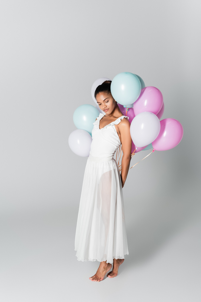 ξυπόλητη χαριτωμένη αφροαμερικάνικη μπαλαρίνα στο φόρεμα με μπαλόνια σε λευκό φόντο - Φωτογραφία, εικόνα