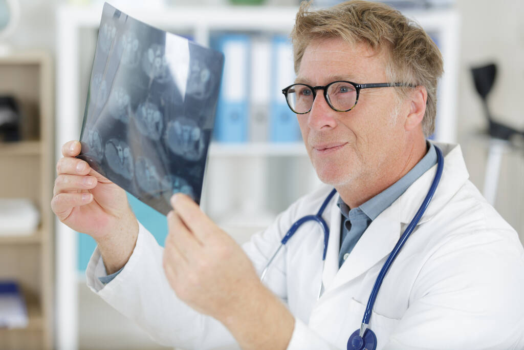 starszy mężczyzna lekarz patrząc na prześwietlenia w szpitalu - Zdjęcie, obraz