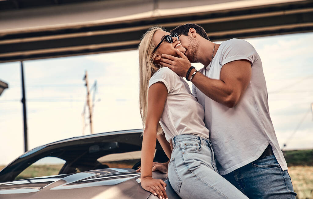 Beau jeune couple en vêtements décontractés près de voiture de sport. - Photo, image