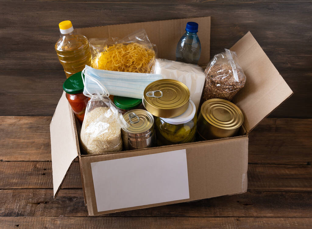 Box with food stock. Cardboard box with butter, canned food, cereals and pasta. Reserve. Donation. - Photo, Image