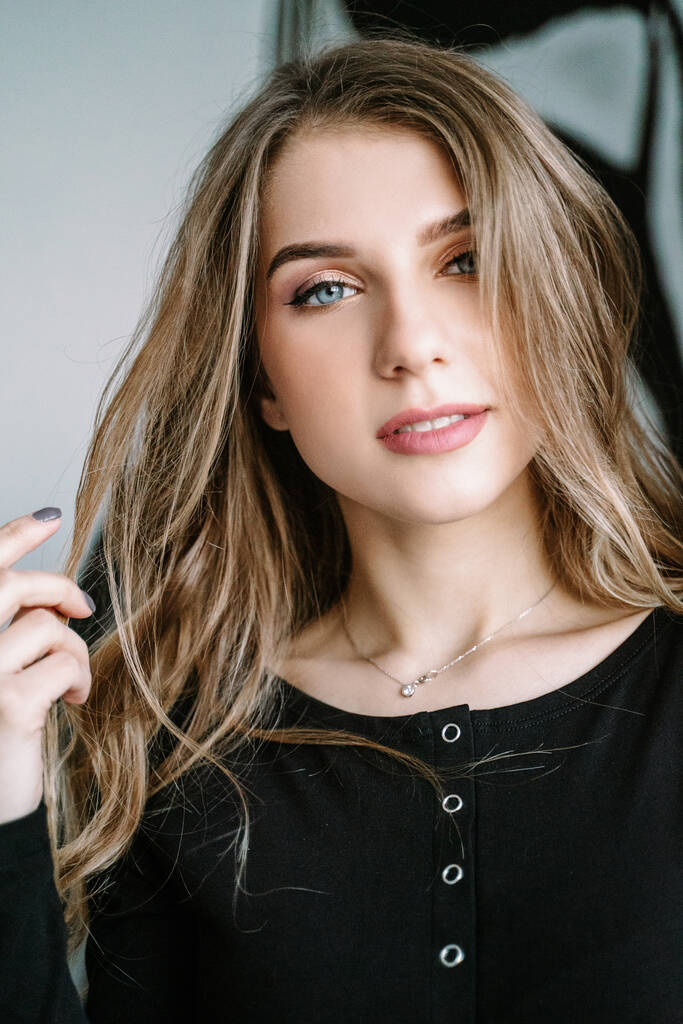 Retrato de una hermosa chica con el pelo largo rubio en una camiseta negra - Foto, Imagen