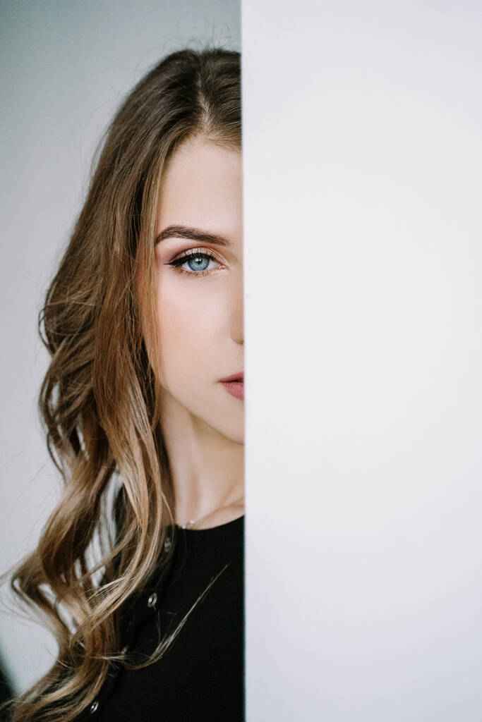 Πορτρέτο ενός όμορφου κοριτσιού με ξανθά μακριά μαλλιά σε μαύρο μπλουζάκι - Φωτογραφία, εικόνα