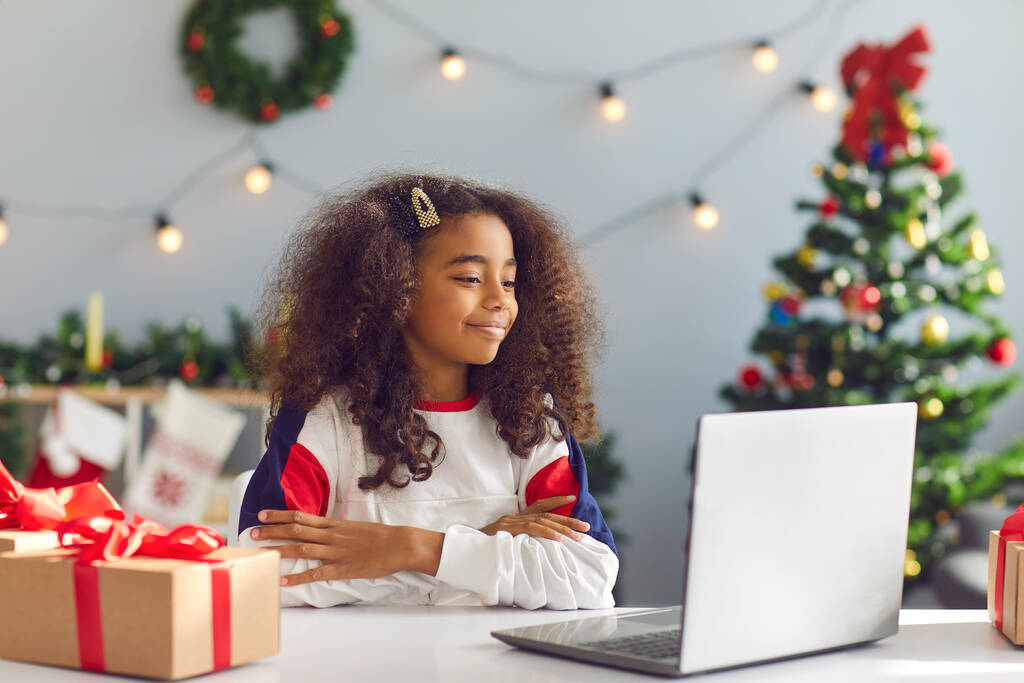 Heureuse fille afro-américaine utilisant un ordinateur portable pour un appel vidéo ou regarder un film de Noël - Photo, image