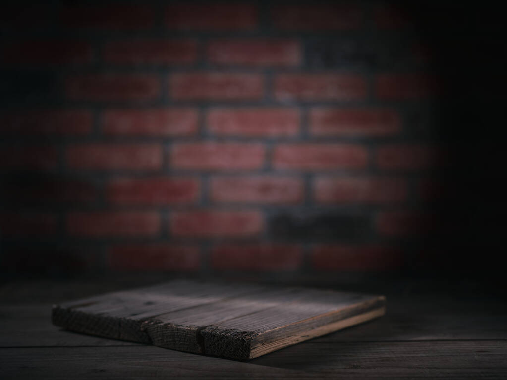 Tabla de cortar sobre una mesa de madera sobre un fondo de pared de ladrillo. Mockup para la presentación del producto. - Foto, imagen