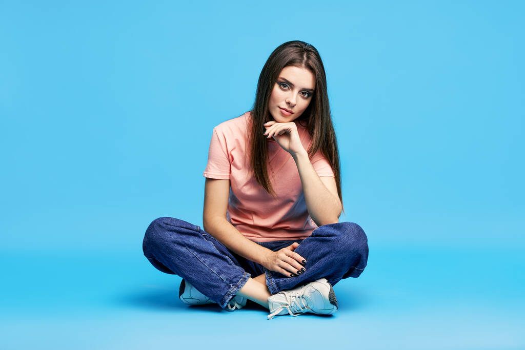 Ziemlich schöne junge Frau posiert im Studio auf dem Boden sitzend - Foto, Bild