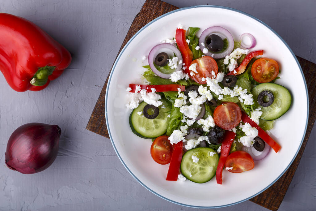 könnyű tányér görög saláta egy fapadlón a zöldségek közelében. Vízszintes fénykép - Fotó, kép
