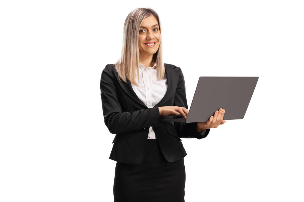 Young blond businesswoman standing and working on a laptop computer isolated on white background - Photo, Image