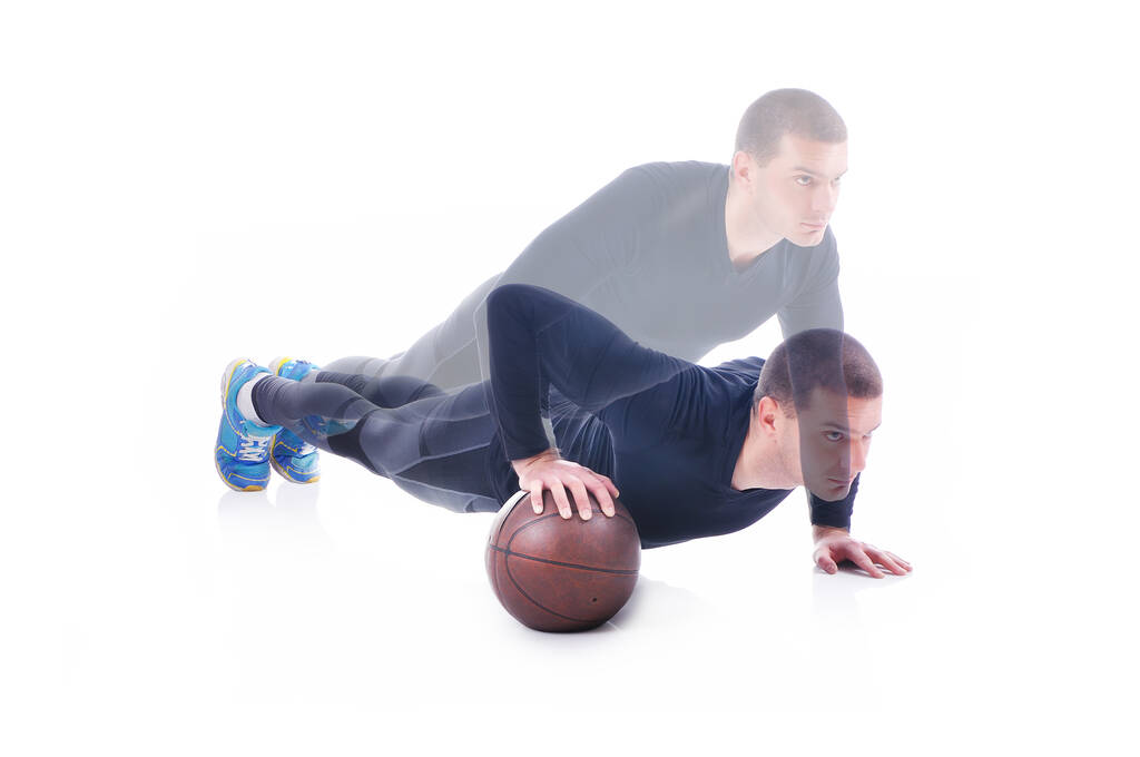 Koncentrált fiatal sportoló gyakorol és fekvőtámaszt csinál a kosárlabdán. Fehér háttér. Stúdió felvétel. Egy kargyakorlat - Fotó, kép