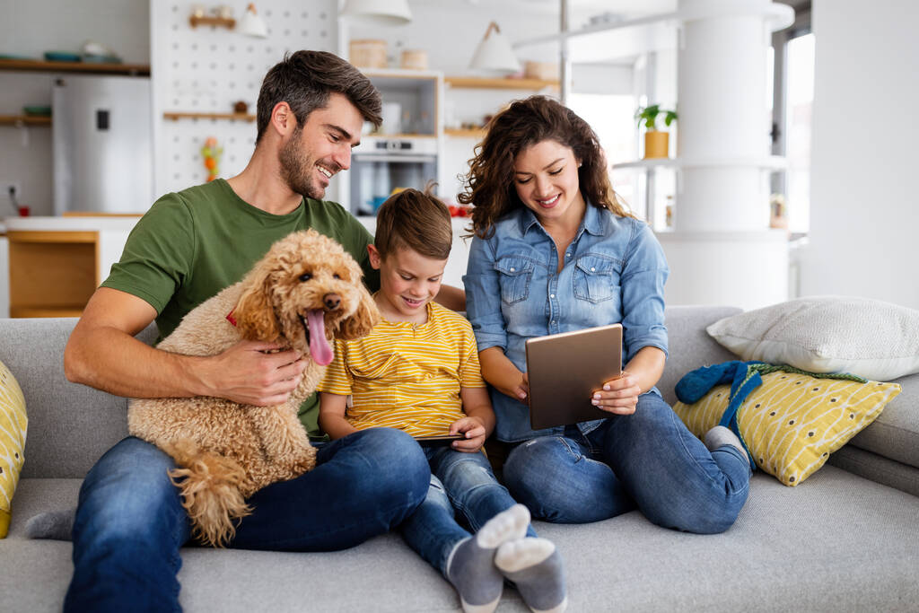 Glückliche junge Familie, die Spaß hat, zu Hause mit Hund spielt - Foto, Bild