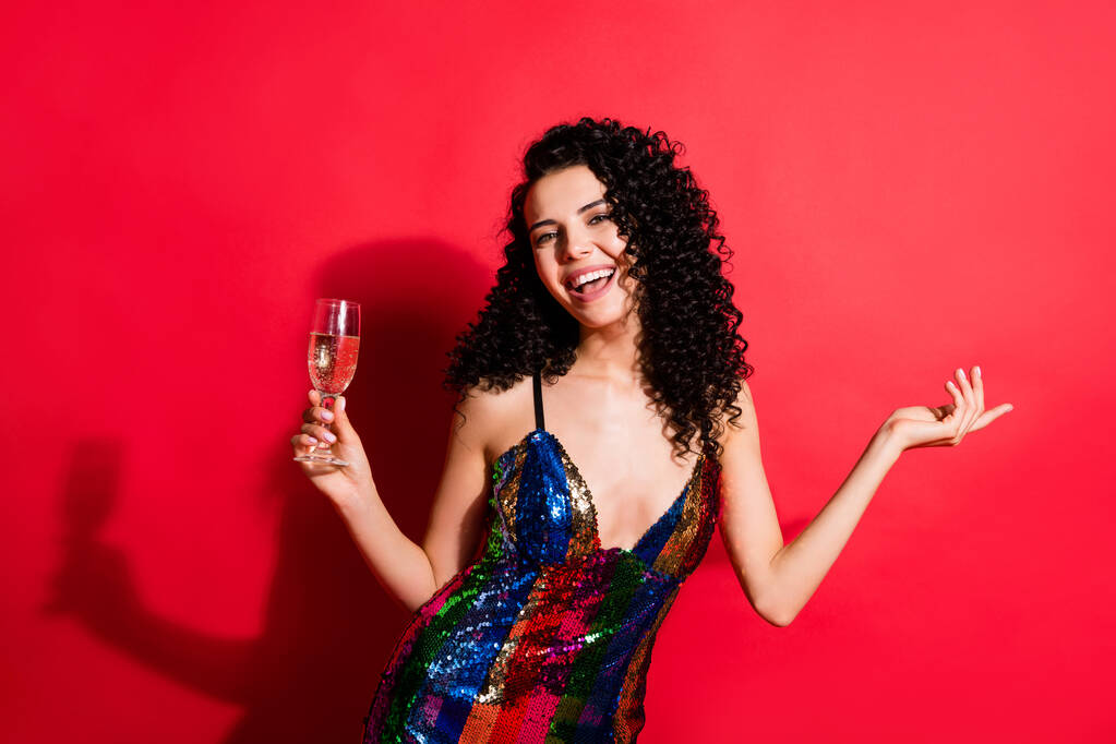 Portret van charmante vrolijk golvend-harig meisje met plezier drinken wijn rust geïsoleerd op heldere rode kleur achtergrond - Foto, afbeelding