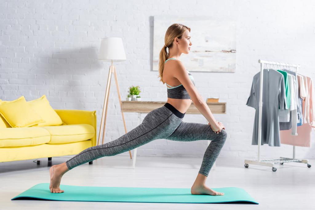 Seitenansicht einer Barfußsportlerin, die zu Hause Yoga praktiziert  - Foto, Bild