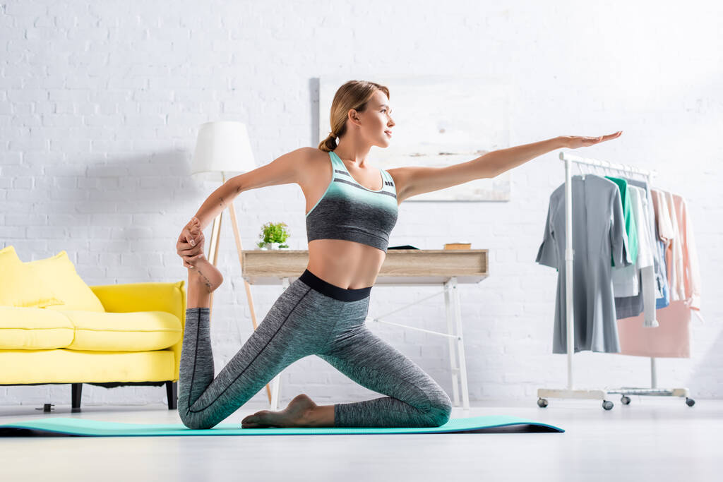 Fit sportive étirement tout en pratiquant le yoga sur tapis à la maison  - Photo, image