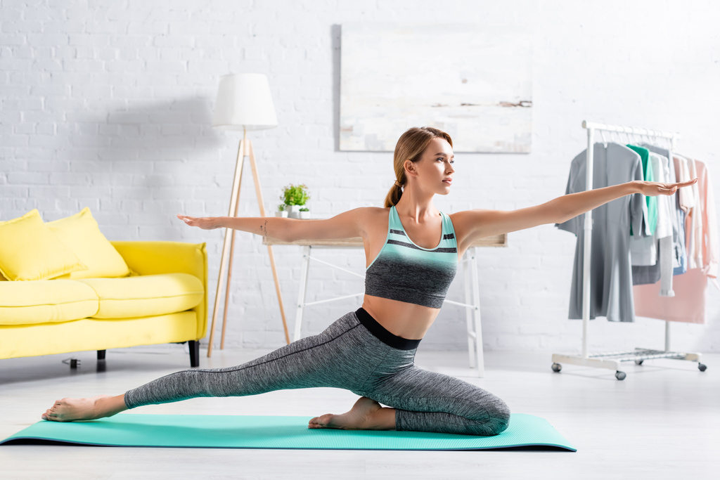 Junge Frau in Sportbekleidung praktiziert Yoga beim Training zu Hause  - Foto, Bild