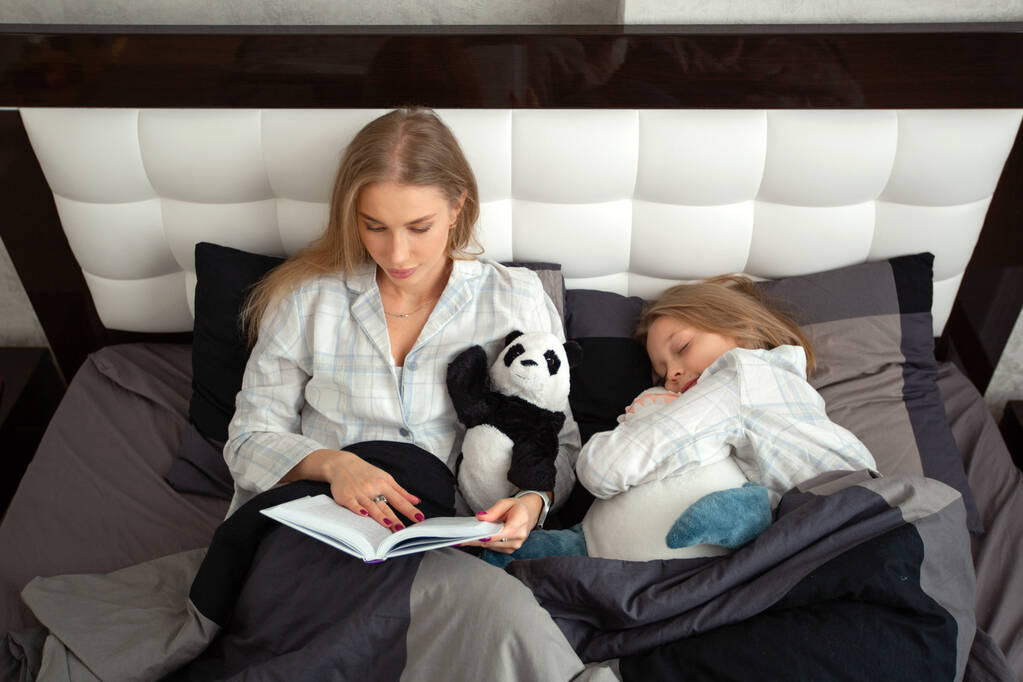 Güzel genç anne gece kızına bir kitap okuyor. - Fotoğraf, Görsel