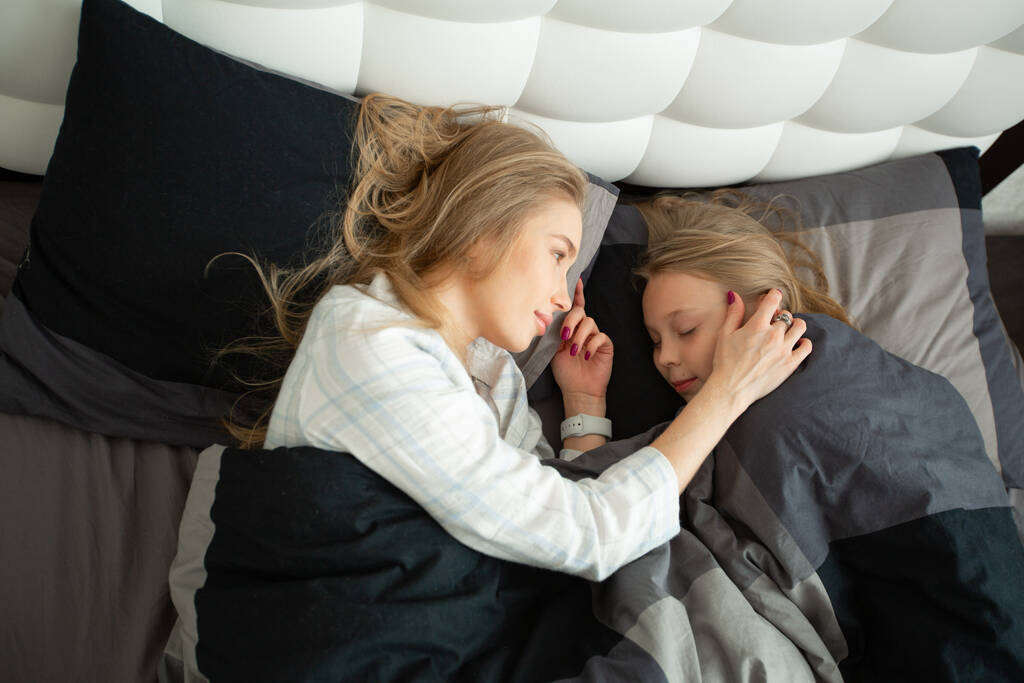 belle maman et fille allongés sur le lit en pyjama - Photo, image