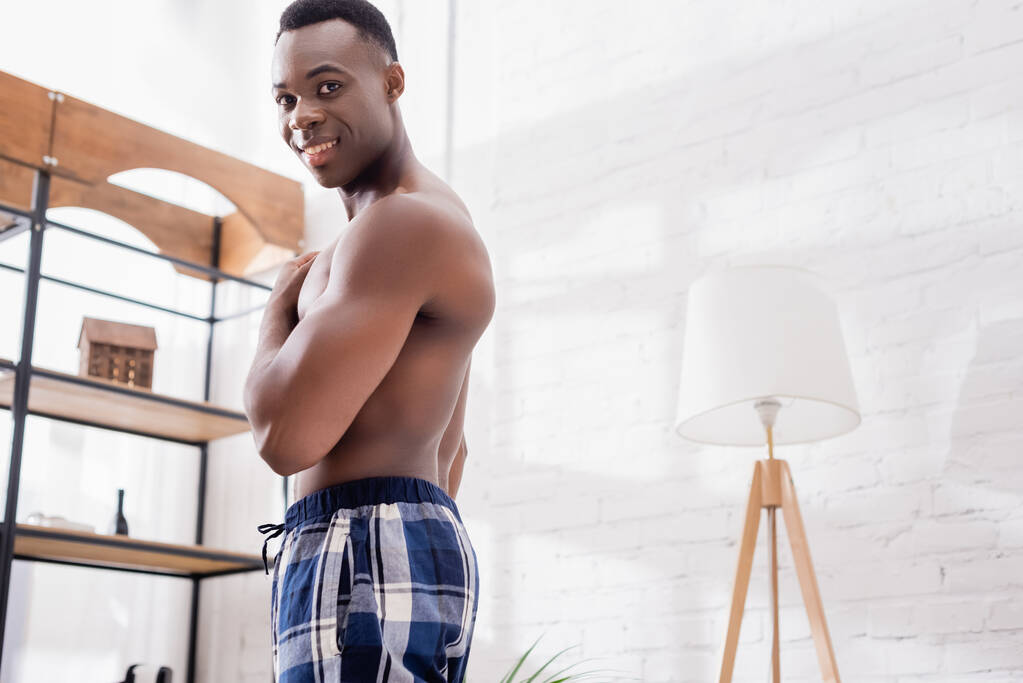 Sans chemise homme afro-américain regardant la caméra à la maison - Photo, image