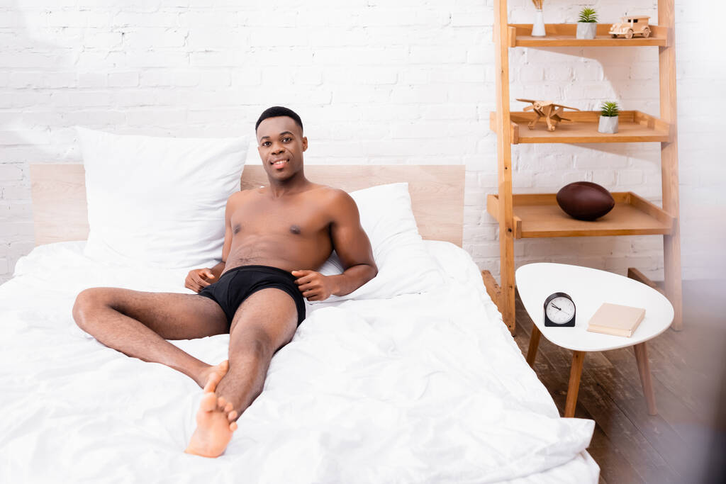 afro americano uomo in biancheria intima guardando fotocamera su letto  - Foto, immagini
