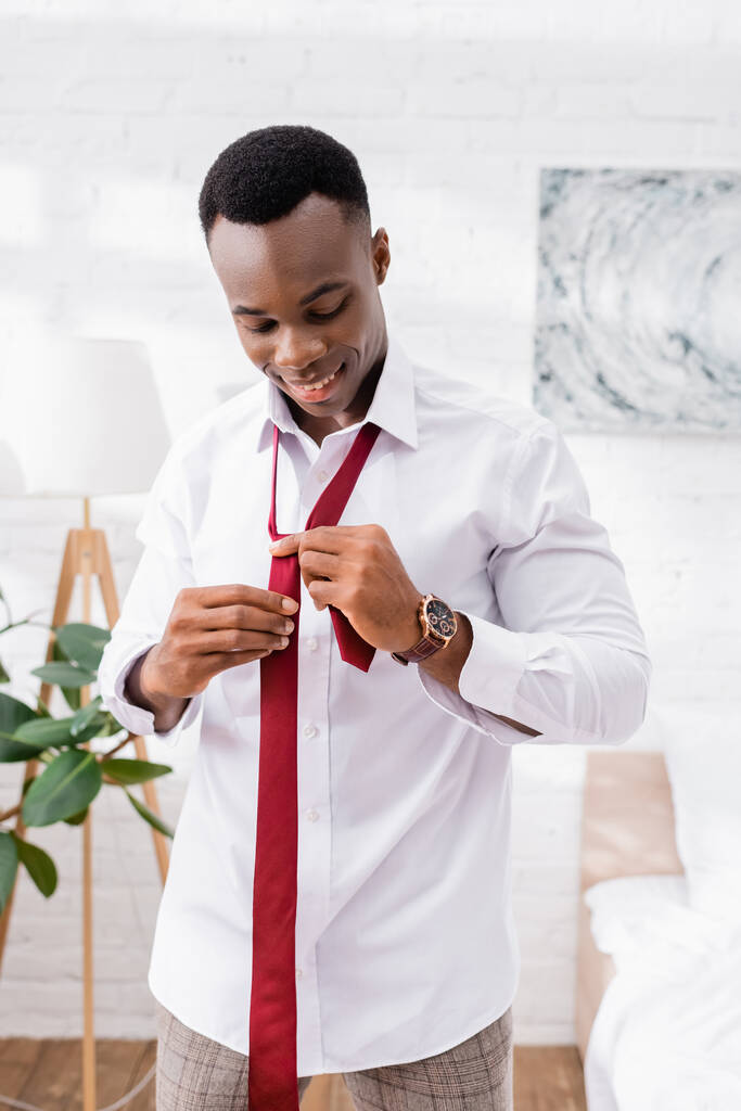 Веселый африканский американский бизнесмен в красном галстуке дома  - Фото, изображение
