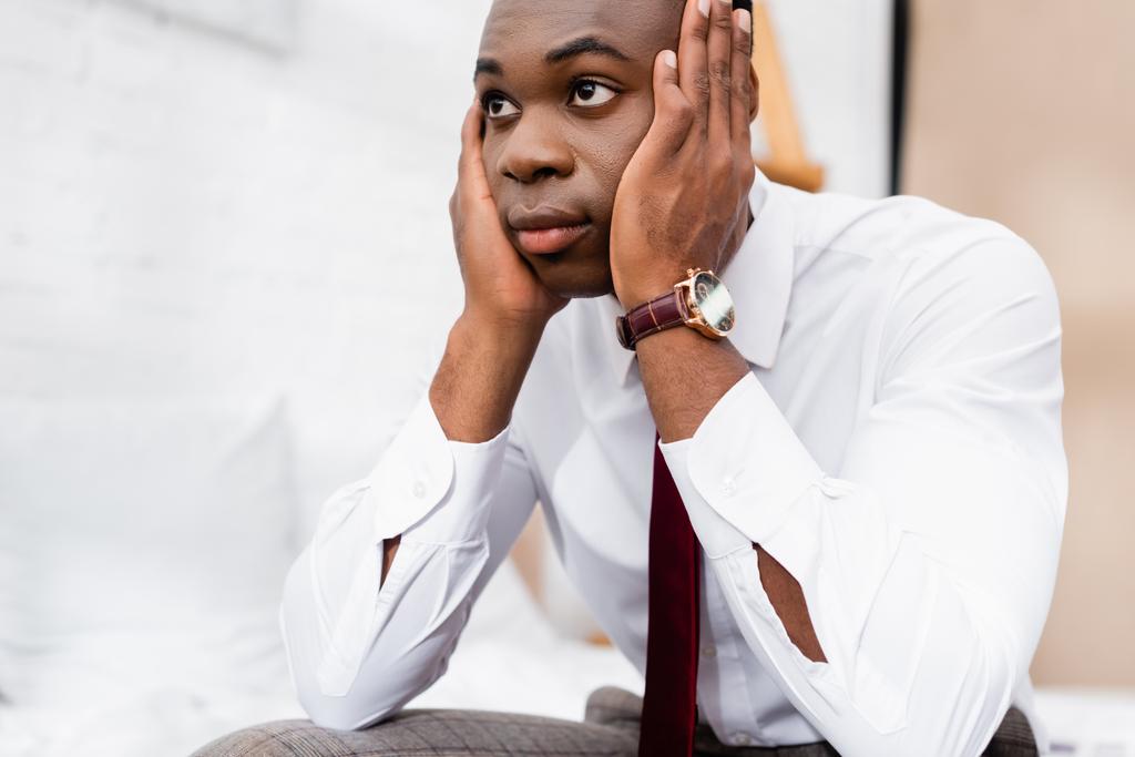 Африканський американський бізнесмен, який тримає руки біля голови, дивлячись убік на будинок.  - Фото, зображення