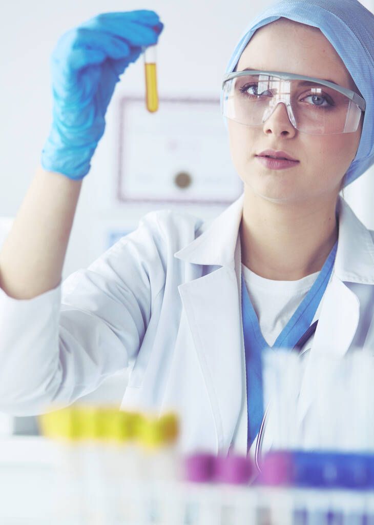 Kobieta badaczka medyczna lub naukowa lub lekarz patrzący na probówkę z przezroczystym roztworem w laboratorium - Zdjęcie, obraz