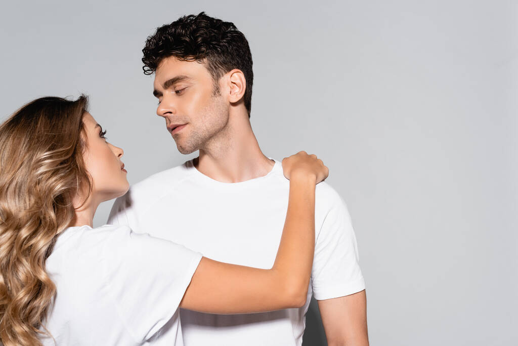 young couple in white t-shirts hugging isolated on grey - Photo, Image