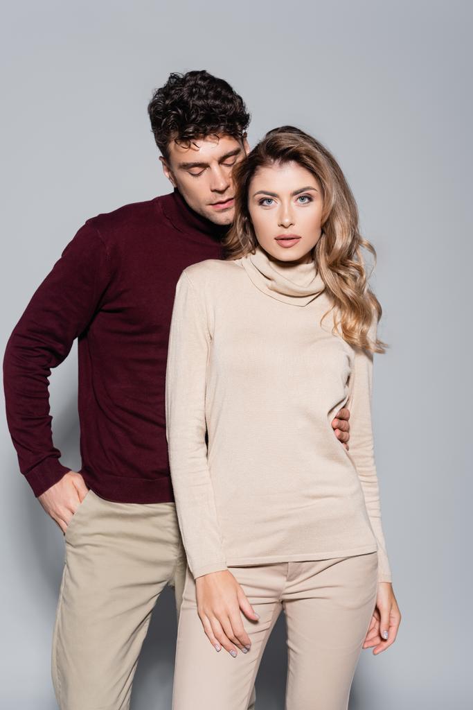 casual young couple in turtleneck jumpers posing isolated on grey - Photo, Image