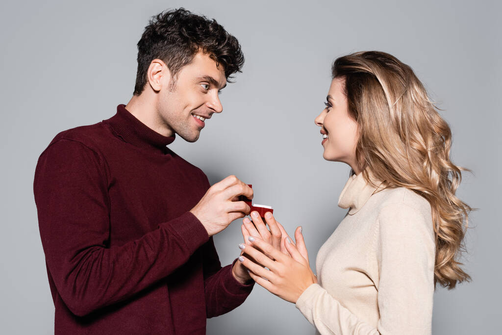 випадковий молодий чоловік робить шлюбну пропозицію щасливій жінці ізольовано на сірому
 - Фото, зображення