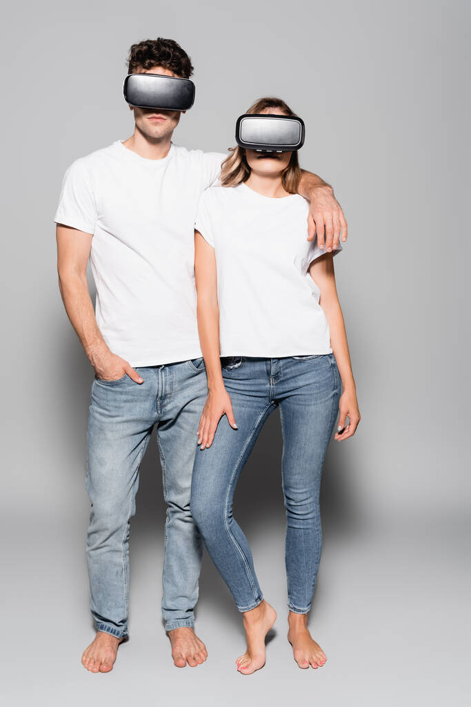 jeune couple décontracté en t-shirts blancs et casques vr isolés sur gris - Photo, image