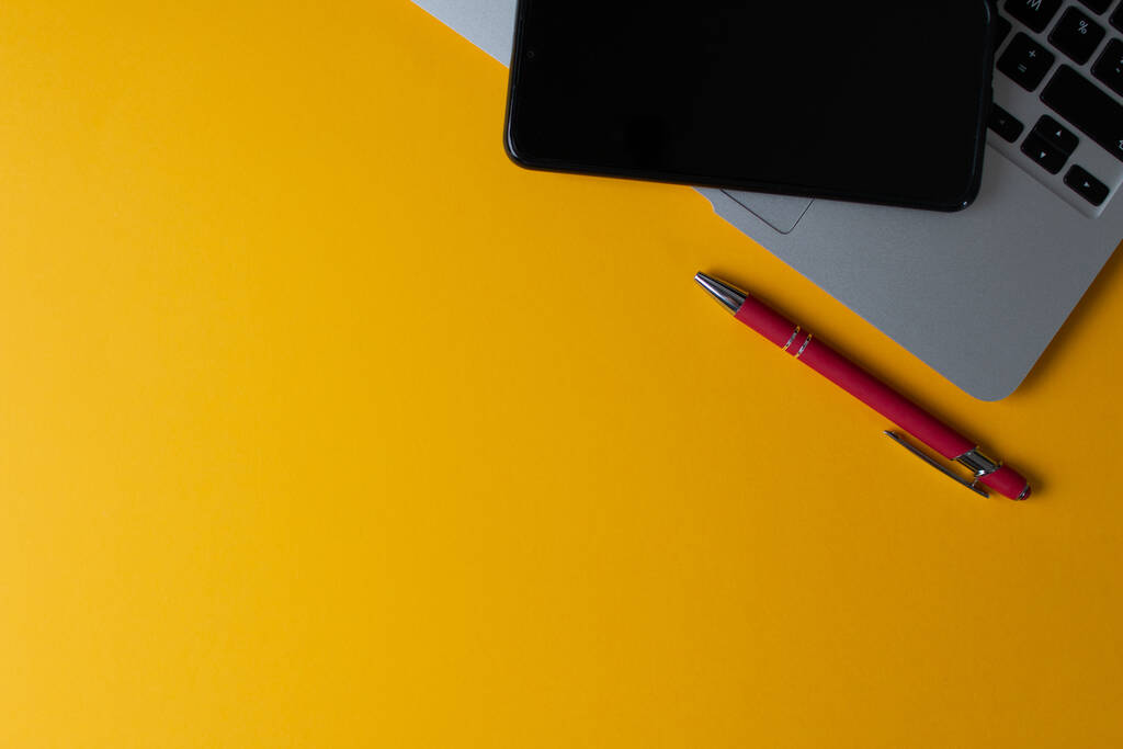 Horní pohled na notebook a mobil na žlutém pozadí - Fotografie, Obrázek