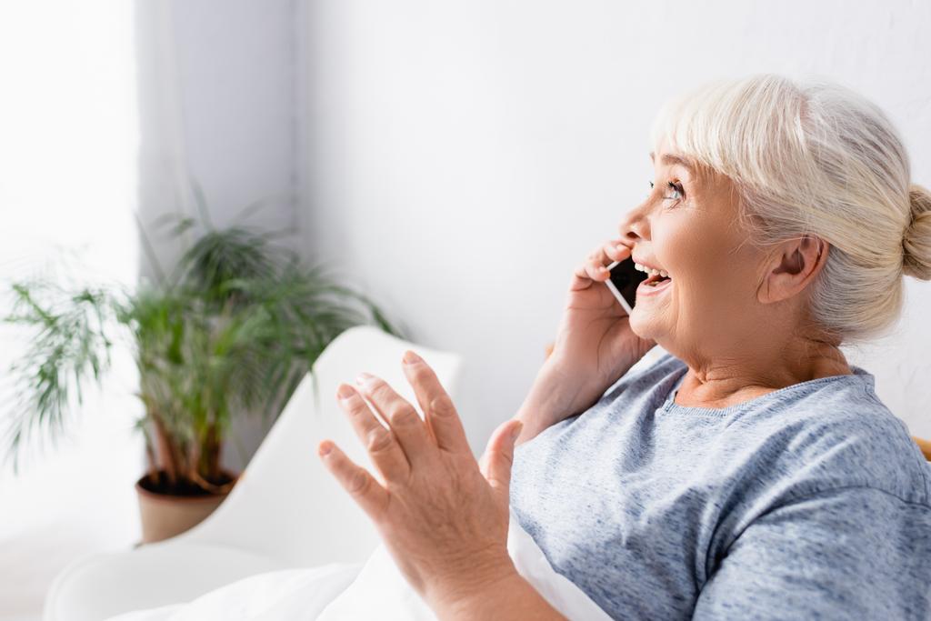 κατάπληκτη ηλικιωμένη γυναίκα μιλάει στο κινητό τηλέφωνο στο νοσοκομείο - Φωτογραφία, εικόνα