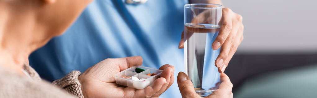 visão parcial da enfermeira dando copo de água e pílulas para paciente idoso, banner - Foto, Imagem