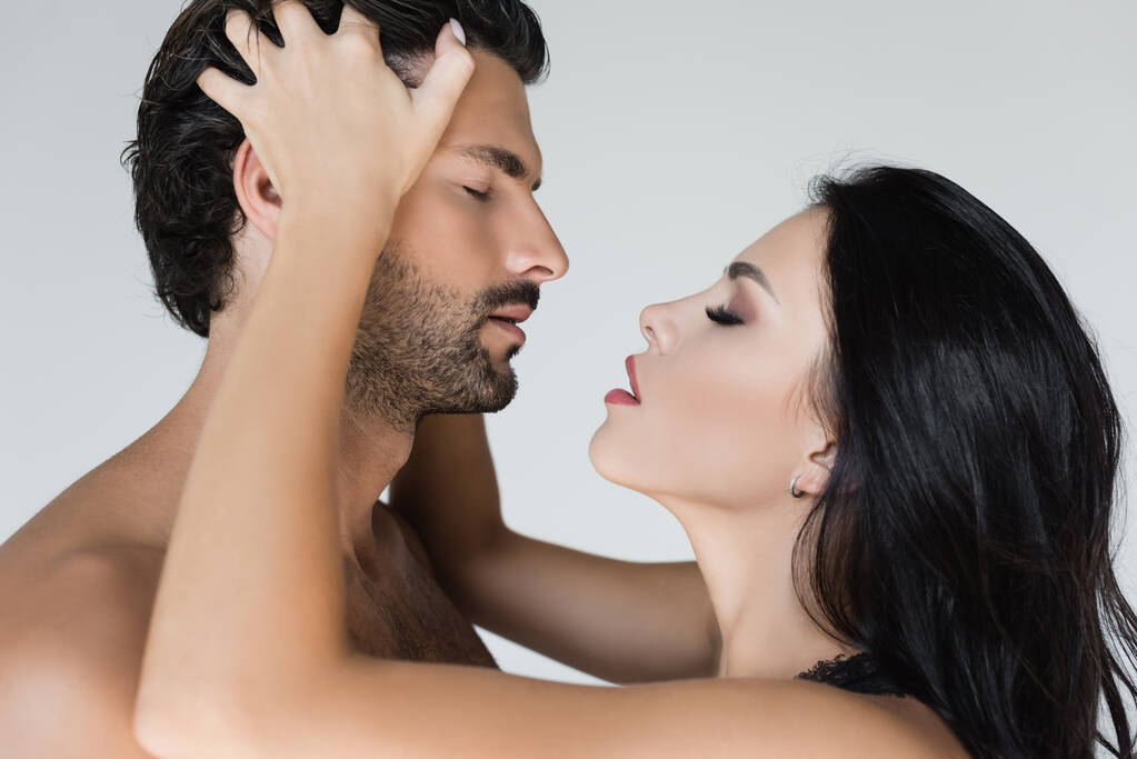 Brunette woman touching head of shirtless man isolated on grey  - Photo, Image