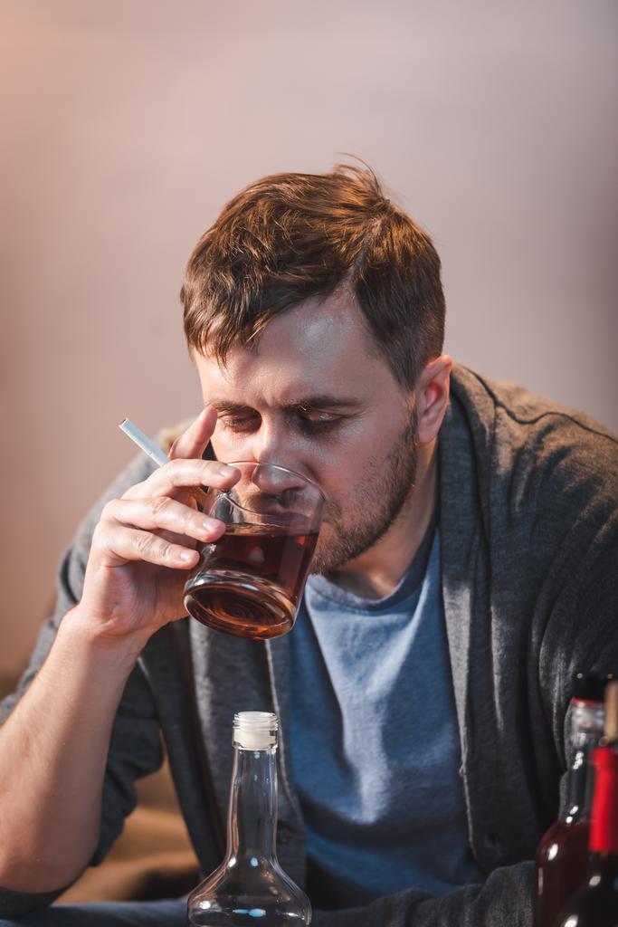 одинокий человек пьет виски, сидя дома один - Фото, изображение